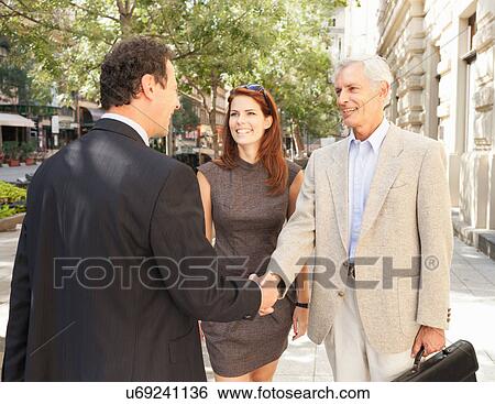 Stock Photograph - Business people shaking hands outdoors. Fotosearch