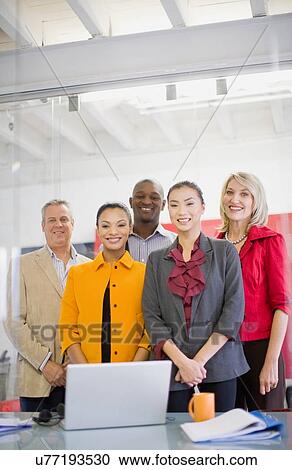 Stock Image - Business people smiling in office. Fotosearch