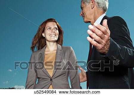 Picture - Business people talking against blue sky. Fotosearch