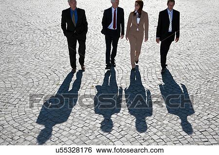 Stock Photograph - Business people walking on cobbled road. Fotosearch