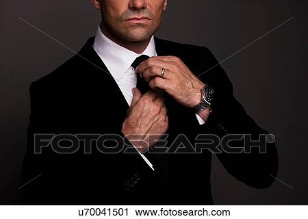 Stock Image - Businessman adjusting his tie. Fotosearch