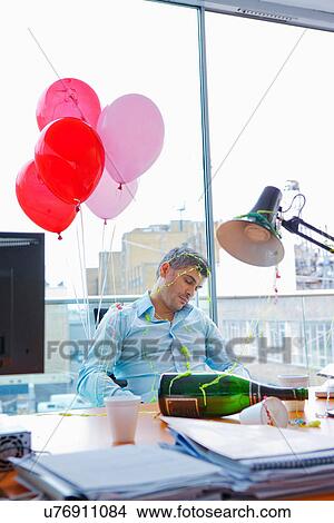 Picture - Businessman asleep at desk after party. Fotosearch