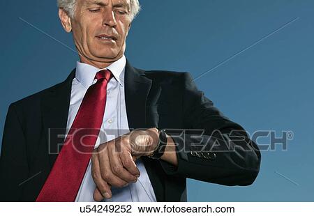 Stock Image - Businessman checking watch outdoors. Fotosearch