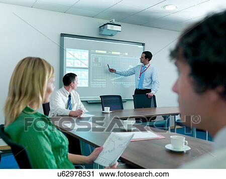 Businessman explaining to colleagues in conference room using smart board View Large Photo Image Stock Image - Businessman explaining to colleagues in conference room using smart board. Fotosearch