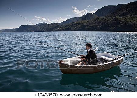 Stock Image - Businessman fishing in rowboat. Fotosearch