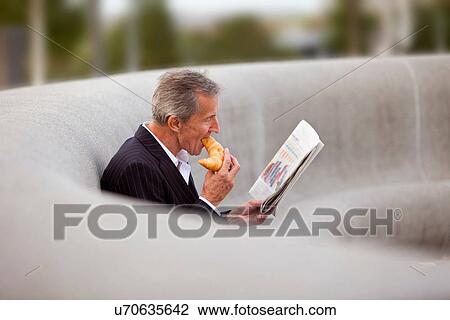 Stock Image - Businessman having breakfast outdoors. Fotosearch