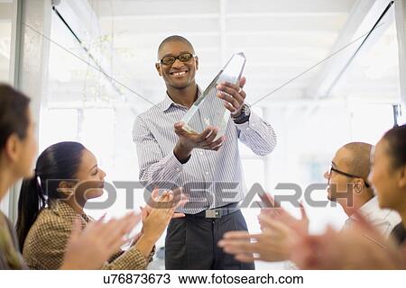 Businessman holding award in meeting View Large Photo Image Stock Image - Businessman holding award in meeting. Fotosearch