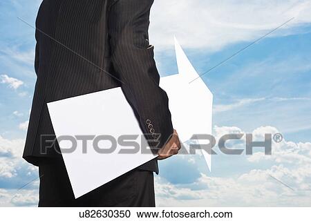 Stock Image - Businessman holding blank arrow. Fotosearch