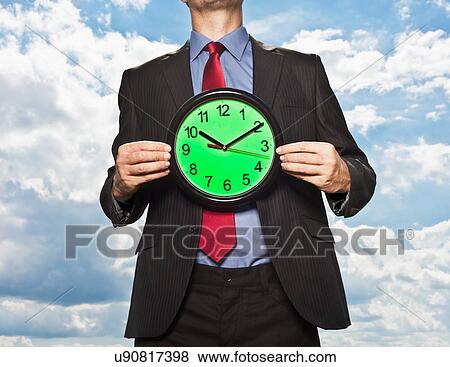 Stock Photo - Businessman holding clock. Fotosearch
