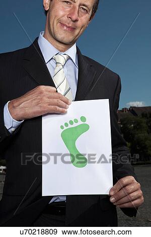 Businessman holding footprint on paper View Large Photo Image Stock Photo - Businessman holding footprint on paper. Fotosearch