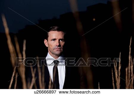 Stock Photo - Businessman in wheat field at night. Fotosearch