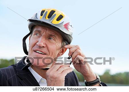 Businessman putting on bicycle helmet View Large Photo Image Picture - Businessman putting on bicycle helmet. Fotosearch
