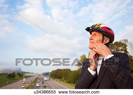 Stock Photography - Businessman putting on bicycle helmet. Fotosearch