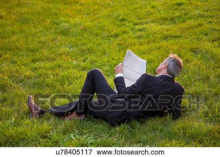 Businessman reading newspaper in grass View Large Photo Image Stock Photo - Businessman reading newspaper in grass. Fotosearch