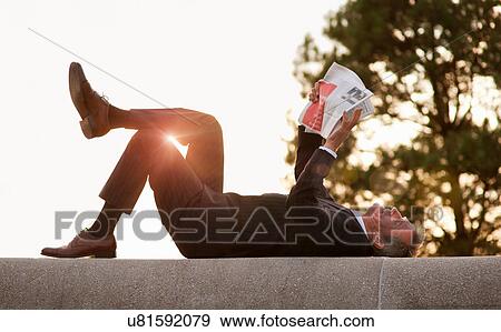 Businessman reading newspaper in park View Large Photo Image Stock Photo - Businessman reading newspaper in park. Fotosearch