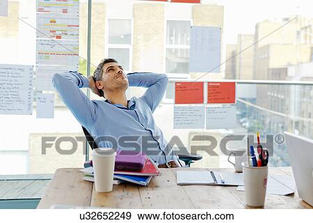 Stock Photo - Businessman relaxing at desk in office. Fotosearch