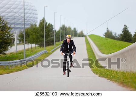 Businessman riding bicycle in urban park View Large Photo Image Stock Image - Businessman riding bicycle in urban park. Fotosearch