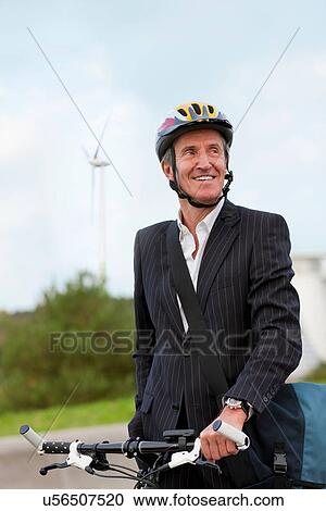 Stock Image - Businessman riding bicycle in urban park. Fotosearch