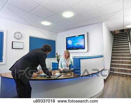 Businessman signing in at office reception View Large Photo Image Stock Photo - Businessman signing in at office reception. Fotosearch