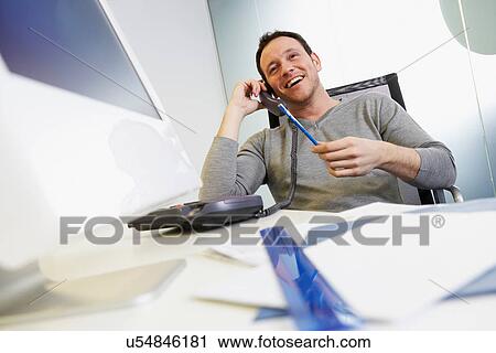 Businessman talking on phone at work View Large Photo Image Stock Image - Businessman talking on phone at work. Fotosearch