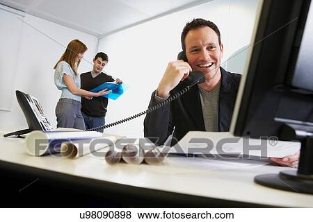 Stock Photo - Businessman talking on phone at work. Fotosearch