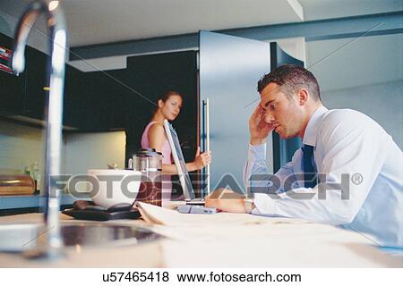 Stock Photo - Businessman using laptop in kitchen. Fotosearch
