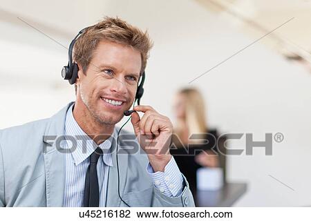 Businessman wearing headset at desk View Large Photo Image Stock Image - Businessman wearing headset at desk. Fotosearch