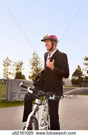 Stock Photography - Businessman with bicycle in urban park. Fotosearch