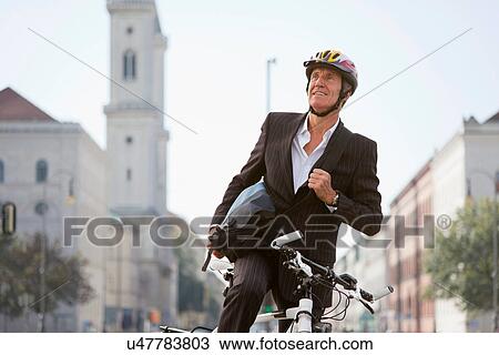 Stock Image - Businessman with bicycle on city street. Fotosearch