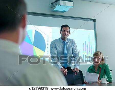 Businessman with presentation on smart board in conference room View Large Photo Image Stock Photo - Businessman with presentation on smart board in conference room. Fotosearch