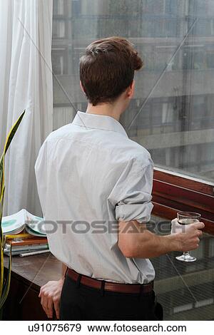 Stock Photo - Businessman with wine looking out window. Fotosearch