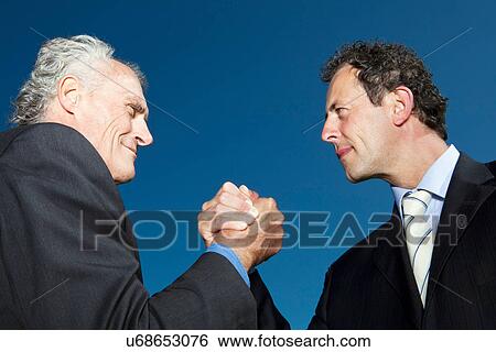 Stock Photograph - Businessmen arm wrestling outdoors. Fotosearch