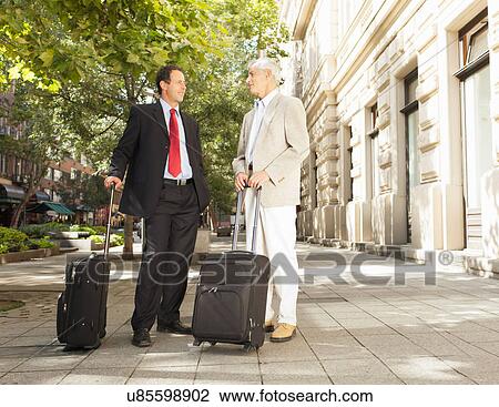 Businessmen rolling luggage outdoors View Large Photo Image Stock Image - Businessmen rolling luggage outdoors. Fotosearch