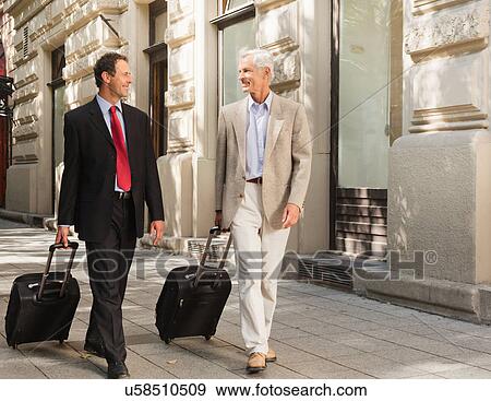 Businessmen rolling luggage outdoors View Large Photo Image Stock Photo - Businessmen rolling luggage outdoors. Fotosearch
