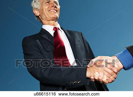 Stock Photograph - Businessmen shaking hands outdoors. Fotosearch
