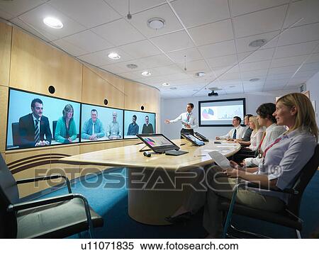 Businesspeople in meeting room taking part in video conference View Large Photo Image Stock Photography - Businesspeople in meeting room taking part in video conference. Fotosearch