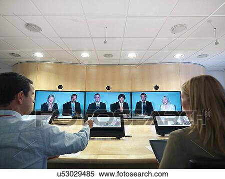 Businesspeople in meeting room using screens in video conference View Large Photo Image Stock Photography - Businesspeople in meeting room using screens in video conference. Fotosearch