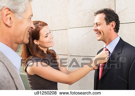 Stock Photo - Businesswoman adjusting colleague's tie. Fotosearch