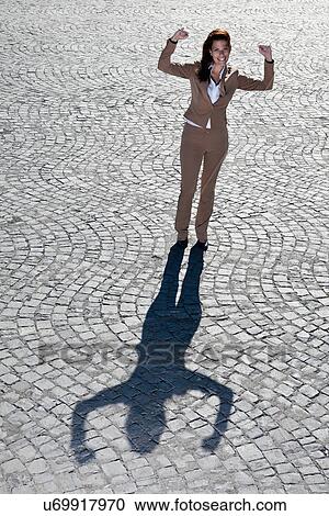 Stock Image - Businesswoman cheering on cobbled road. Fotosearch