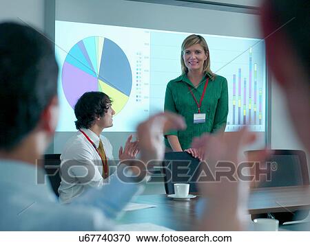 Stock Image - Businesswoman congratulated by colleagues in conference room for smart board presentation. Fotosearch