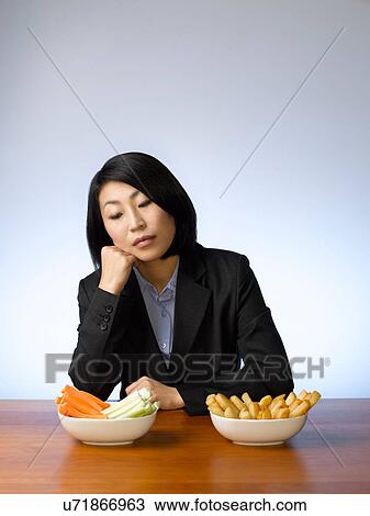 Stock Image - Businesswoman deciding what to eat. Fotosearch