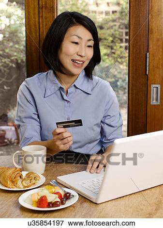 Stock Photo - Businesswoman eating and shopping online. Fotosearch