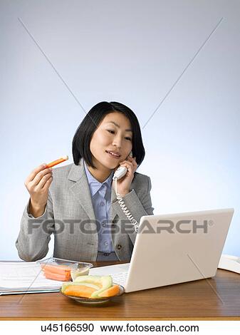 Businesswoman eating and working at desk View Large Photo Image Stock Image - Businesswoman eating and working at desk. Fotosearch