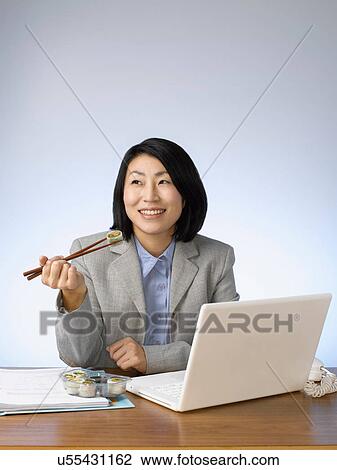 Businesswoman eating and working at desk View Large Photo Image Stock Image - Businesswoman eating and working at desk. Fotosearch