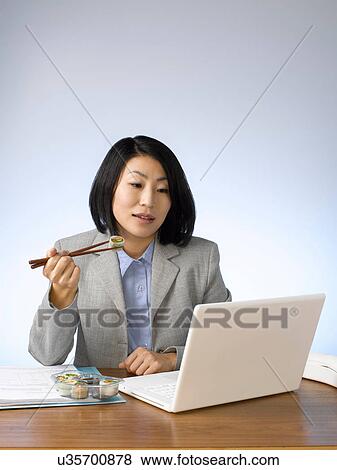 Businesswoman eating and working at desk View Large Photo Image Stock Photo - Businesswoman eating and working at desk. Fotosearch