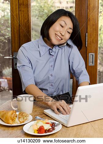 Stock Photo - Businesswoman eating and working. Fotosearch