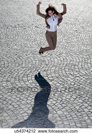 Businesswoman jumping on cobbled road View Large Photo Image Stock Image - Businesswoman jumping on cobbled road. Fotosearch