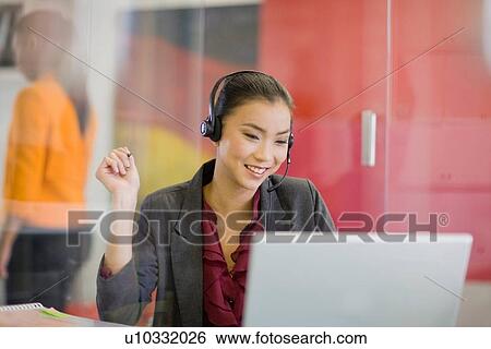 Businesswoman on headset using laptop View Large Photo Image Stock Photograph - Businesswoman on headset using laptop. Fotosearch
