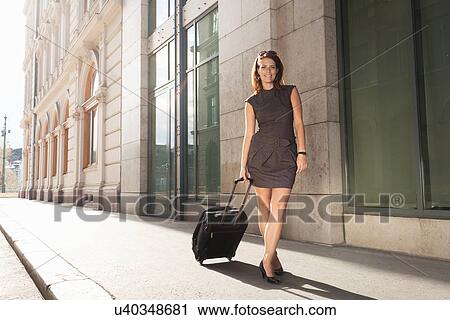 Businesswoman rolling luggage outdoors View Large Photo Image Stock Image - Businesswoman rolling luggage outdoors. Fotosearch