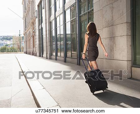 Businesswoman rolling luggage outdoors View Large Photo Image Stock Image - Businesswoman rolling luggage outdoors. Fotosearch